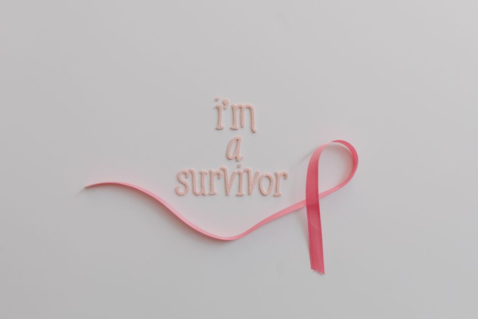 Pink ribbon with 'I'm a survivor' message symbolizing breast cancer awareness on white background.