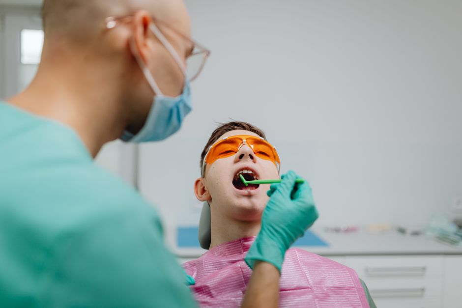 Dentist performing a dental checkup on a patient wearing protective eyewear.