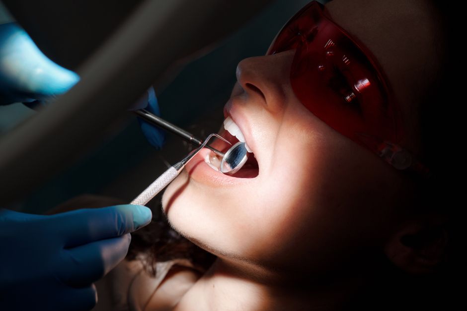 A detailed close-up of a dental examination showing tools and a patient with protective eyewear.