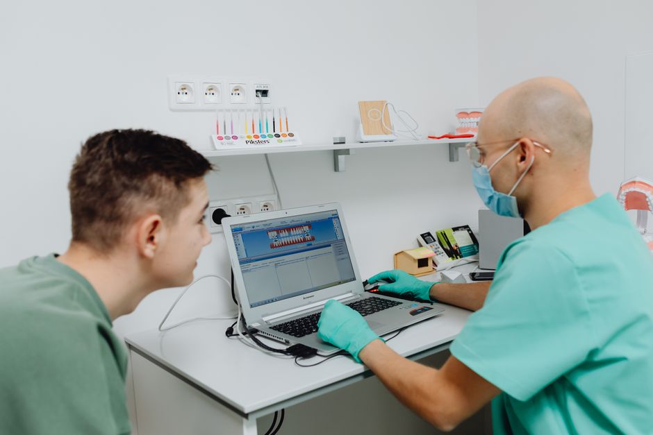 Dentist consulting a patient using laptop in a modern dental clinic setting.