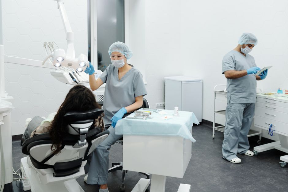 A dentist and assistant in a clinic attending to a patient with professional care.