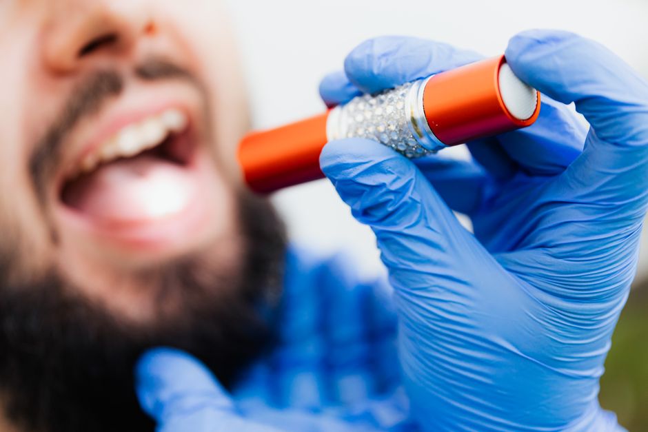 Gloved hands holding a flashlight during a dental examination, showcasing close-up detail.
