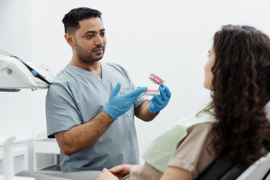 Dentist showing a dental model to a patient in a clinical setting.