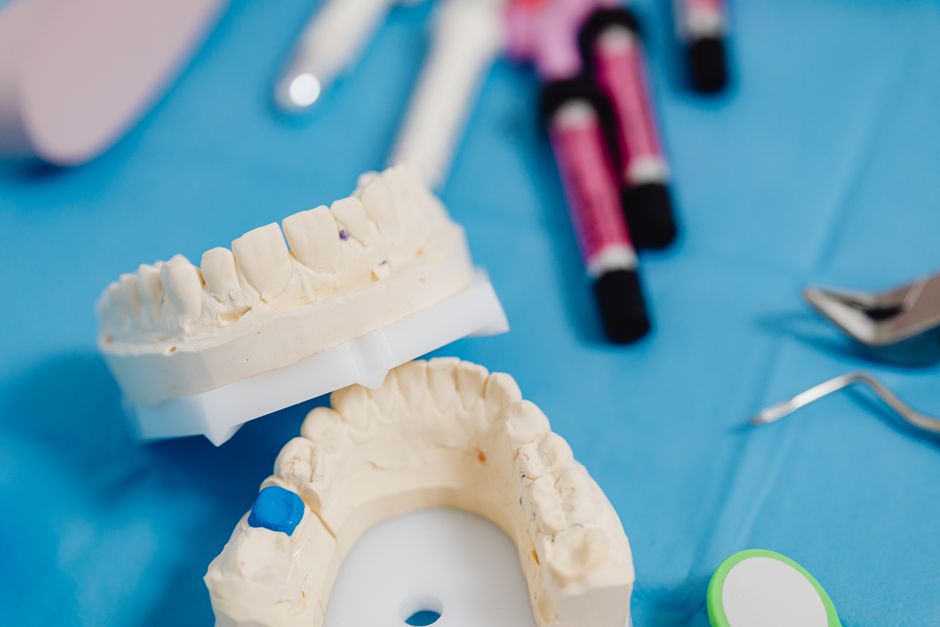 Dental jaw model with dental tools on a blue cloth for dental education and practice.