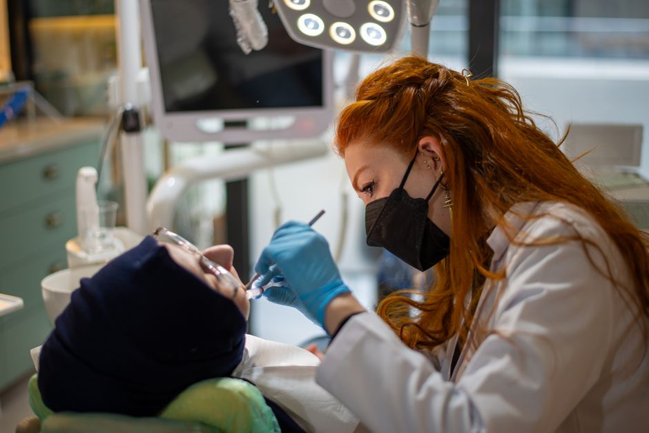 A female dentist focused on treating a patient in a modern, well-equipped dental clinic.