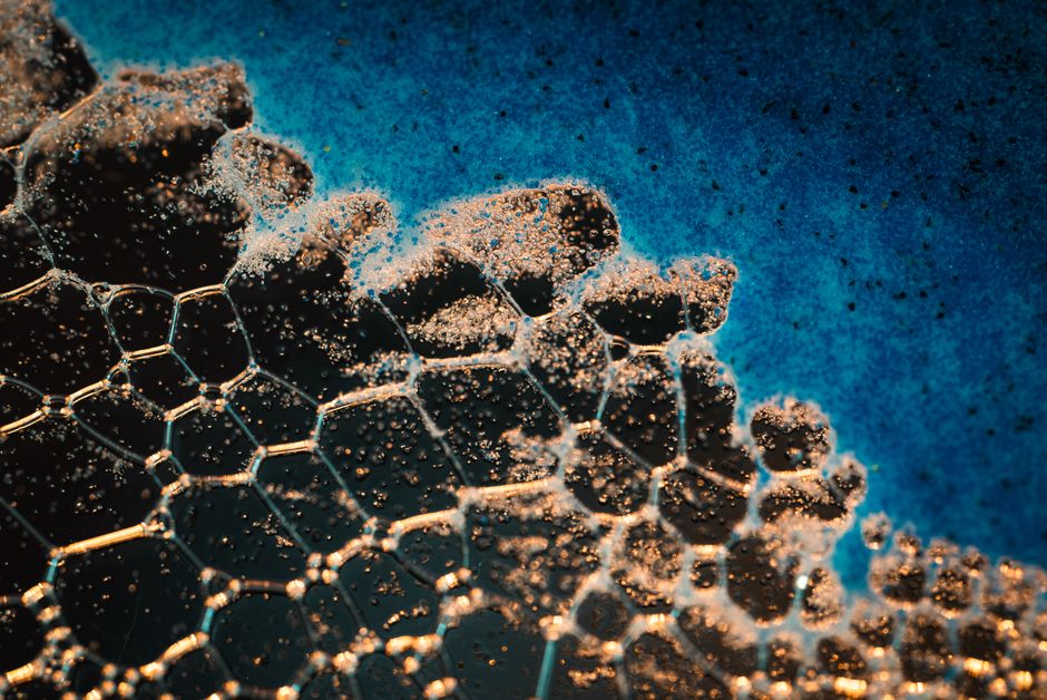 Intricate close-up of soap bubbles creating abstract patterns on a blue background.
