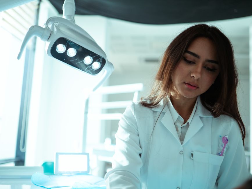 Female dentist in a modern dental clinic with equipment, focused on patient care.