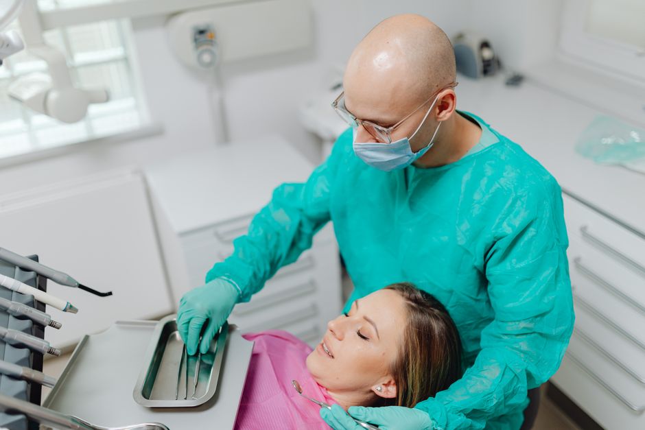 Dentist in protective gear examines patient in modern clinic setting.