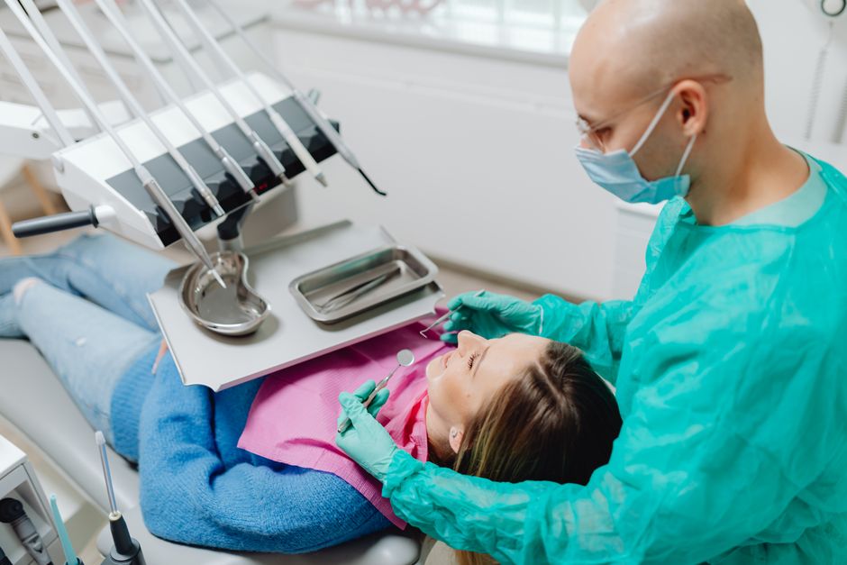 A dentist in a clinic performing a routine checkup on a patient using dental tools.