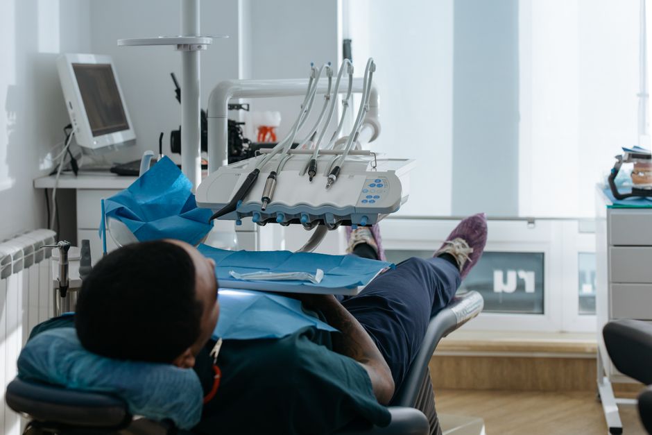 A patient in a dental clinic positioned in a dental chair for a checkup with dental equipment visible.
