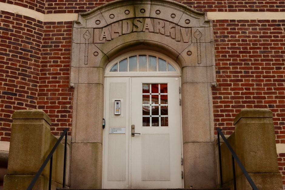 Close-up of a historic building entrance with stone arch and brick wall.