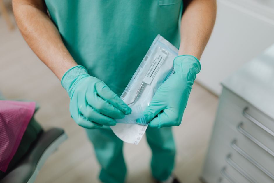 Close-up of a dental professional unpacking sterile instruments in a clinic.