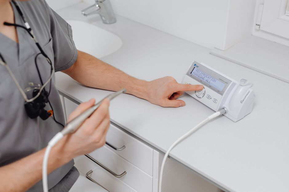 Close-up of a dental professional operating a modern medical instrument in a clinic setting.