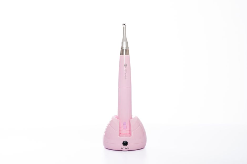 Dental handpiece device in pastel pink isolated on white for clinical use.