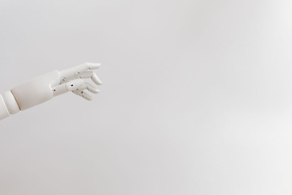 Minimalist image of a robotic hand reaching out on a white background.