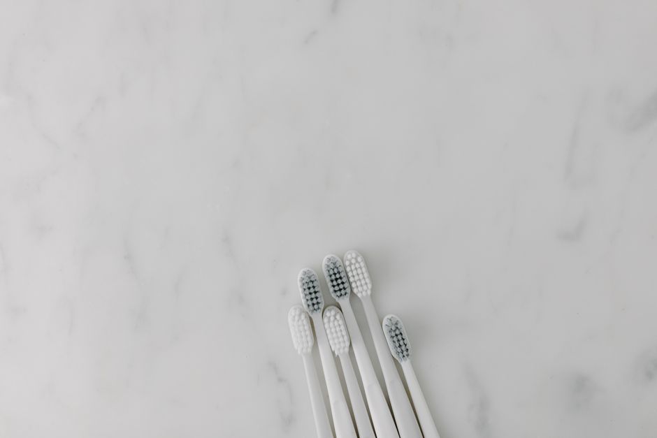 Five white toothbrushes arranged on a marble surface, offering a clean and minimalist aesthetic with ample copy space.