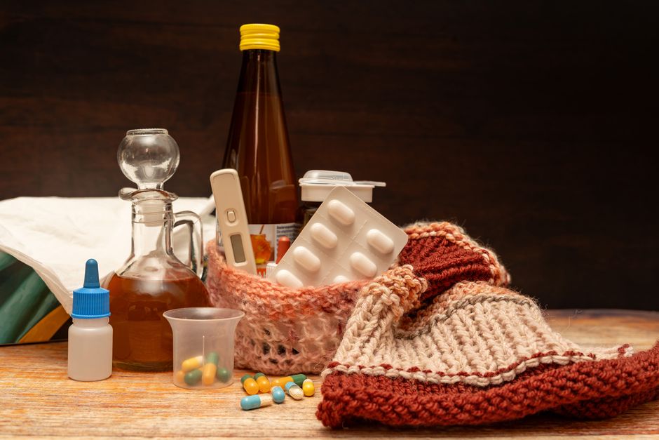 A warm collection of medications and items for cold and flu relief set on a wooden surface.