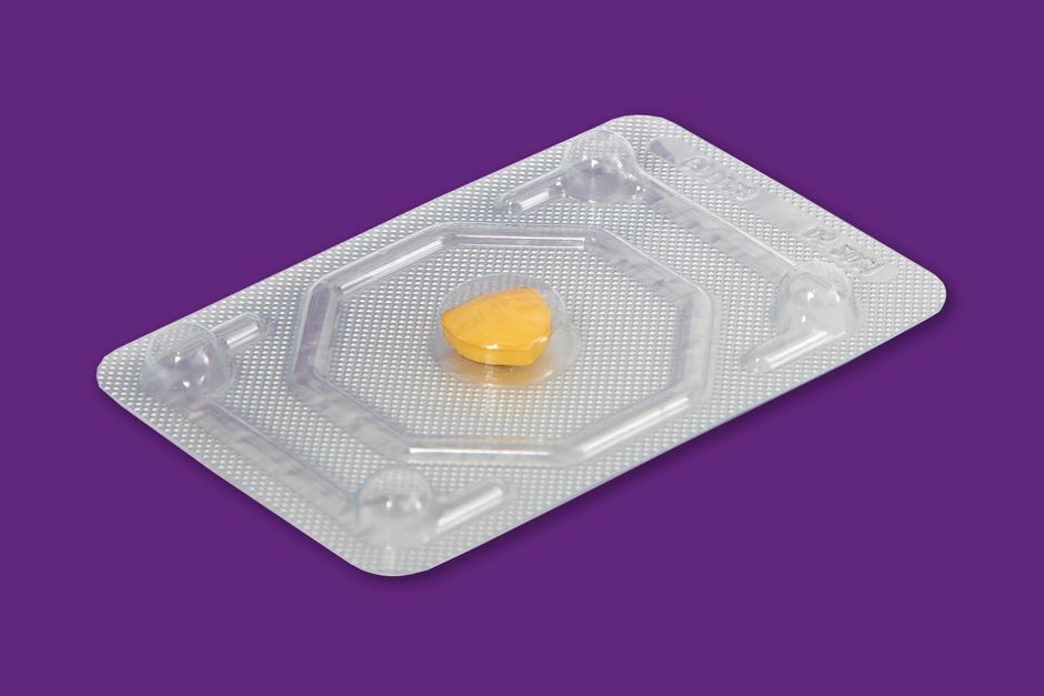 A yellow pill in a blister pack on a vibrant purple background, representing healthcare.
