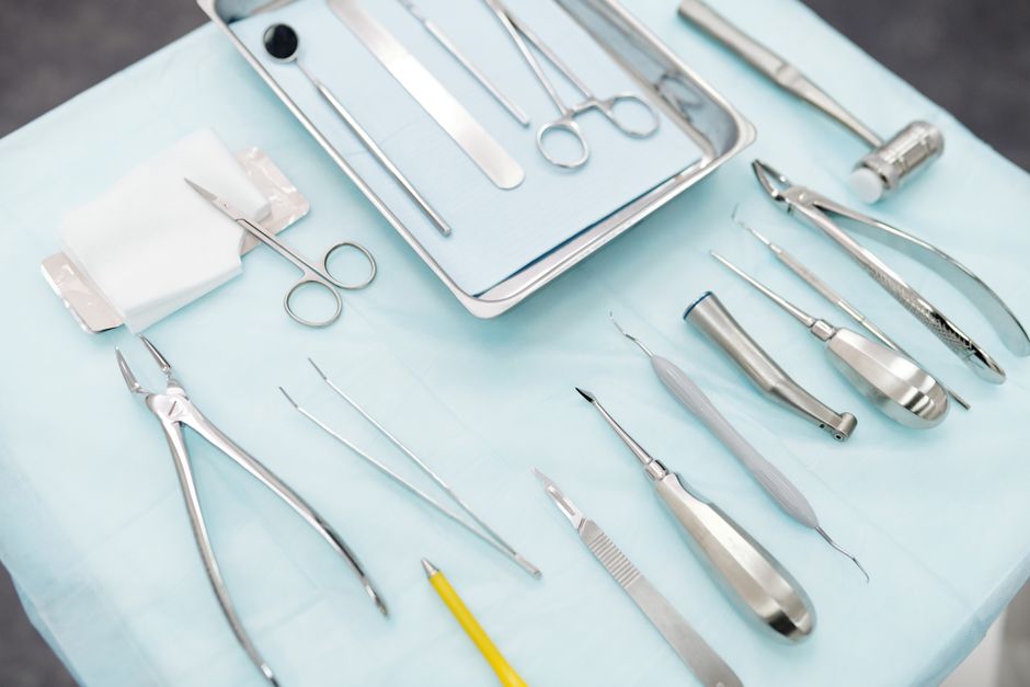 A set of shiny stainless steel dental tools neatly arranged on a blue cloth.