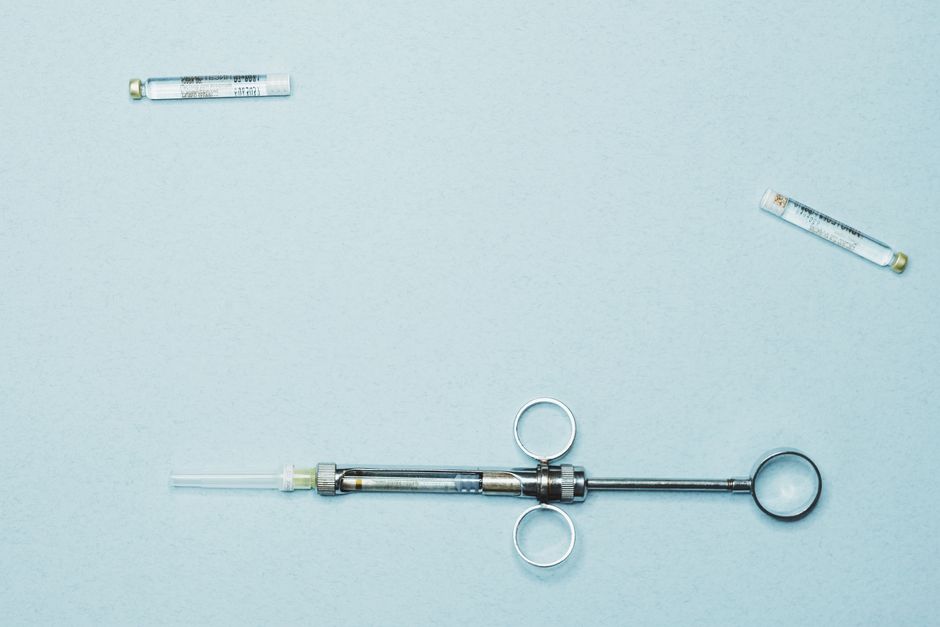High-quality stock photo of a dental syringe and vials on a blue background. Ideal for dentistry.