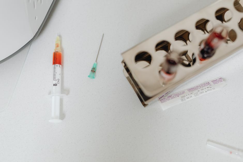 Syringe and needle with blood samples in a laboratory setting, capturing healthcare diagnostics.