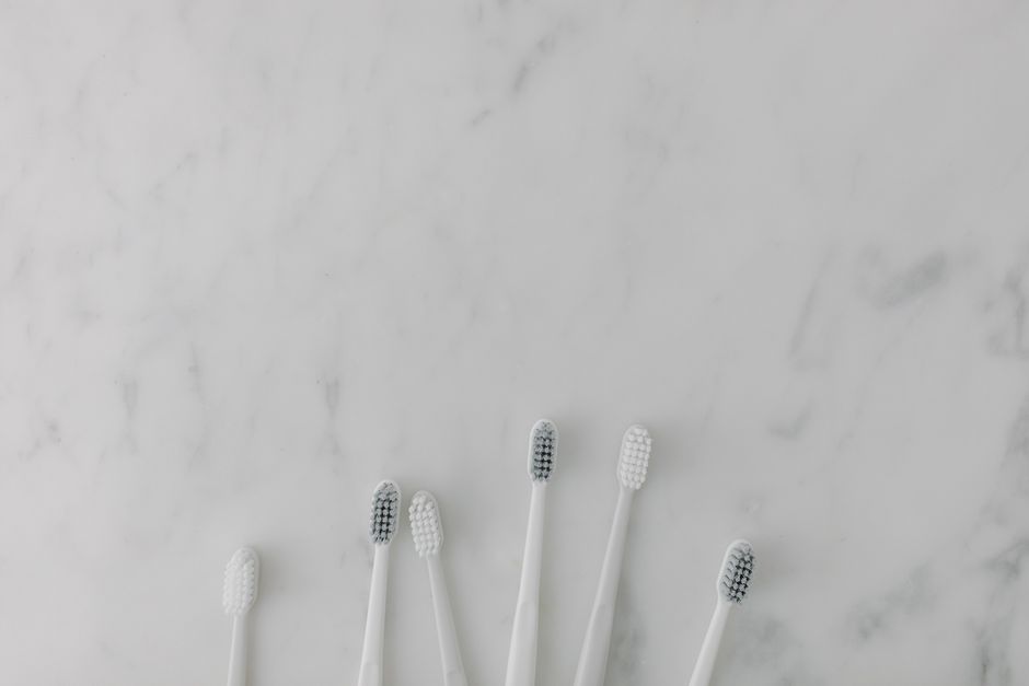 Five minimalist toothbrushes arranged on a marble surface, perfect for dental care themes.
