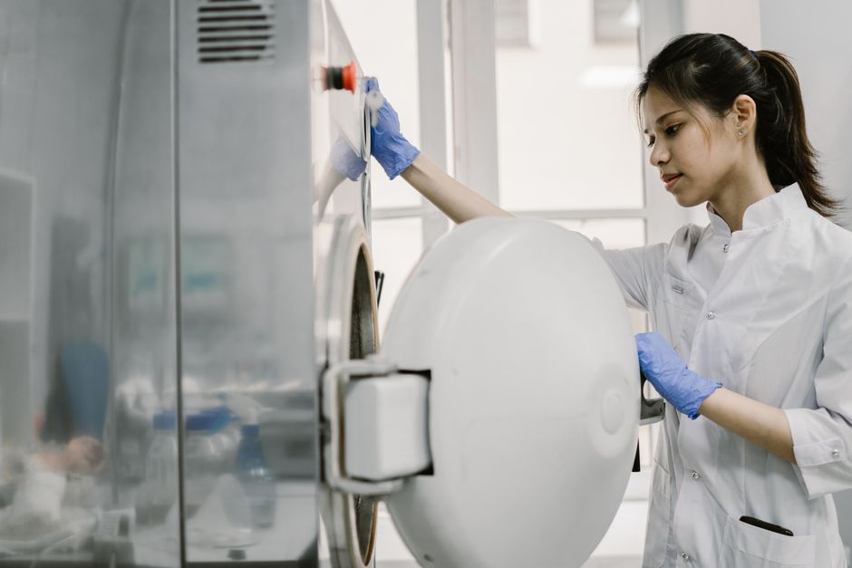 Scientist in lab coat uses industrial equipment, showcasing technology in laboratory setting.