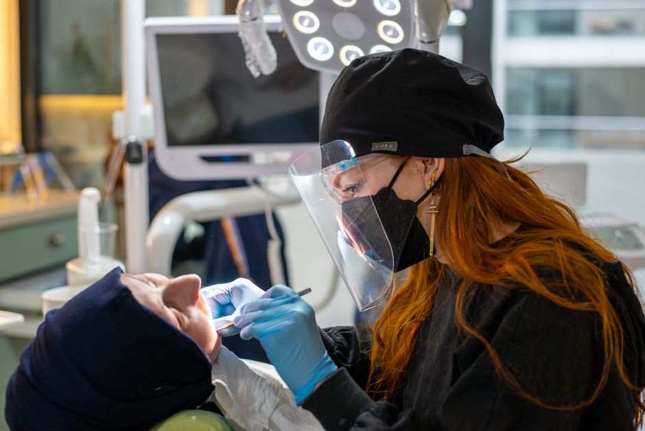A dentist in protective gear performing a dental procedure in a modern clinic.