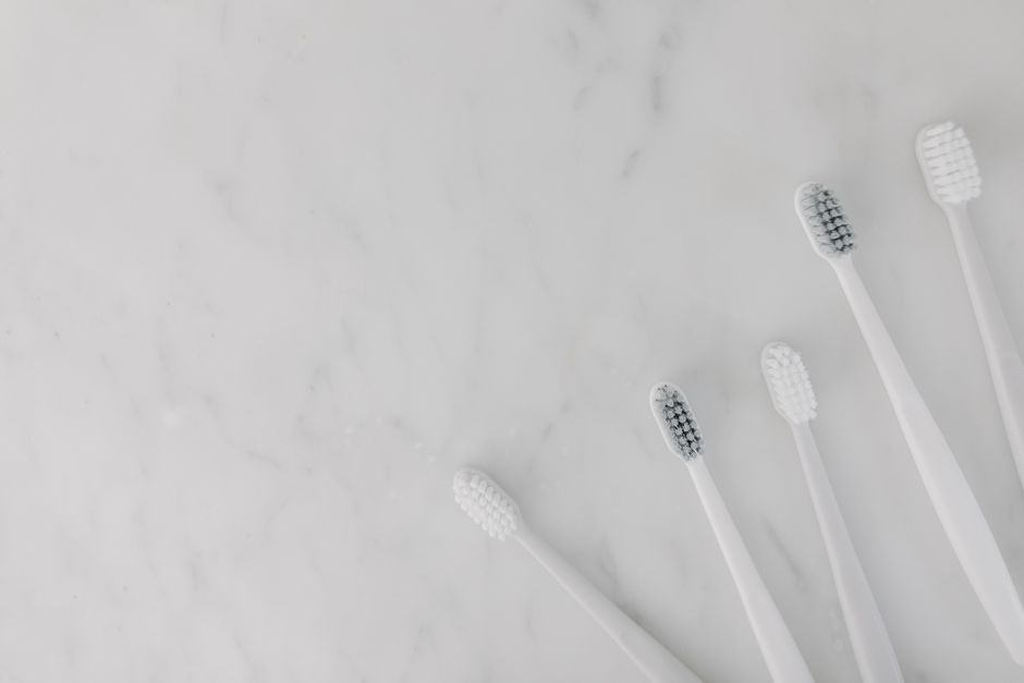 Elegant display of white toothbrushes on a marble surface, emphasizing hygiene and simplicity.