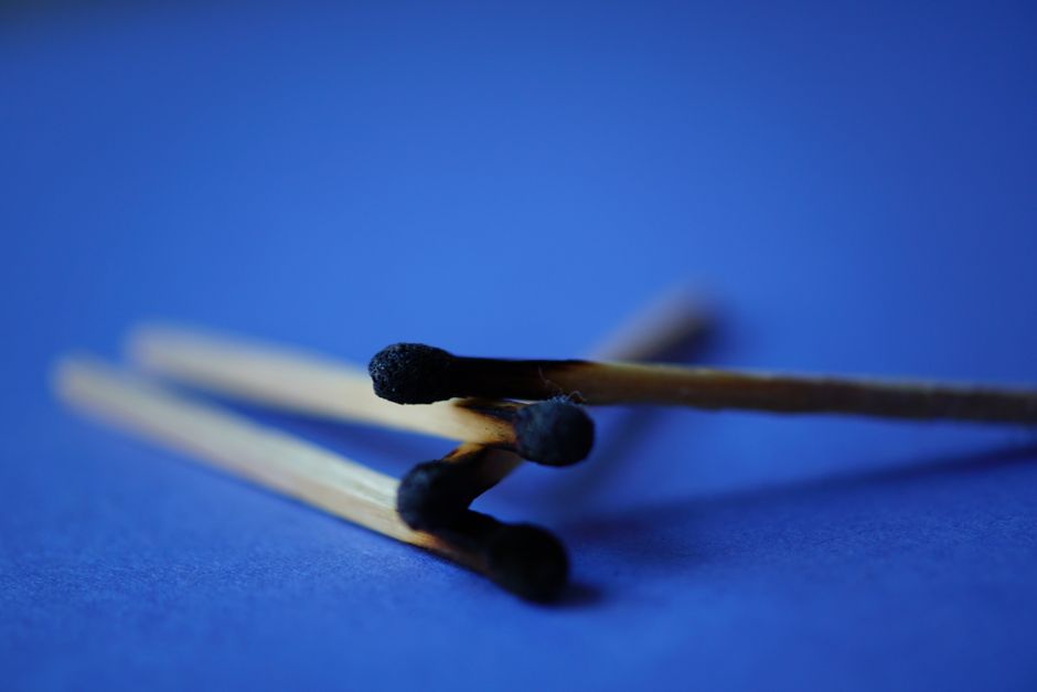 Detailed macro shot of burnt wooden matchsticks on a blue surface.