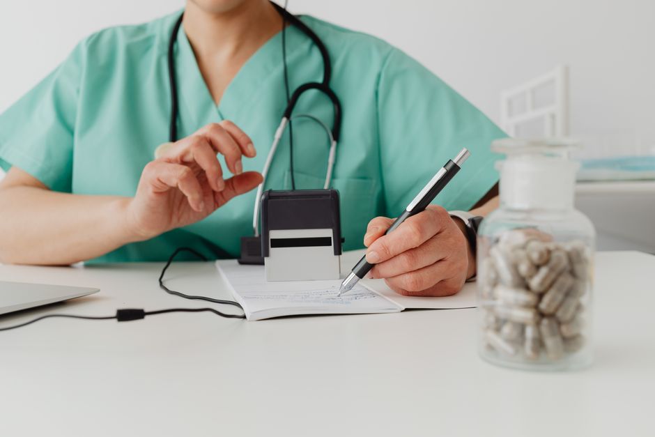 A medical professional writing a prescription in a clinical setting.