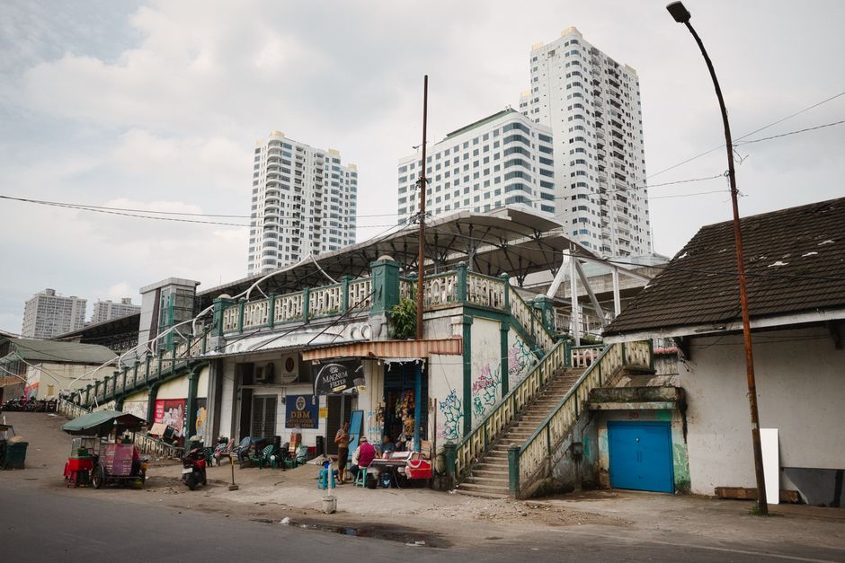 A bustling street view in Medan with market activity and towering buildings in the background.