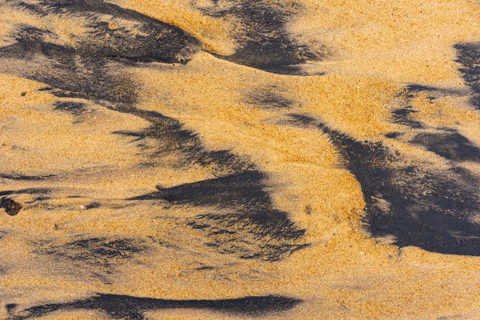 Detailed close-up of sand textures with ilmenite on a beach, highlighting natural patterns.