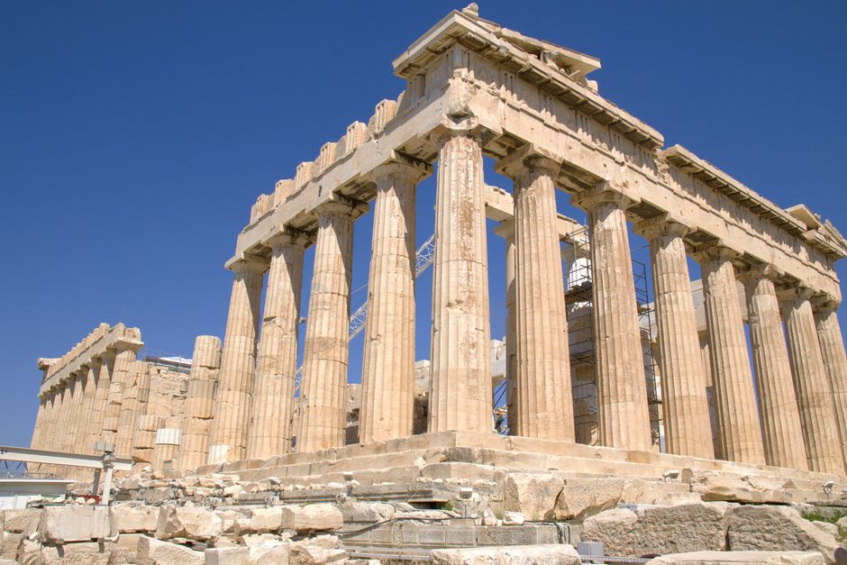 A view of the Parthenon in Athens showcasing its ancient Greek architecture against a bright blue sky.