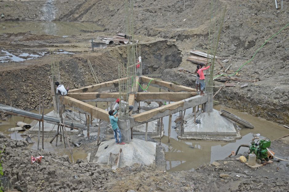 Workers constructing a building foundation with rebar and wooden supports outdoors.