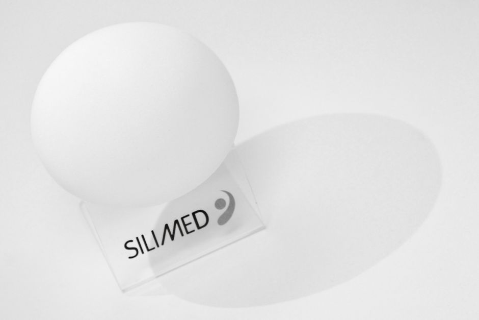 Minimalist white sphere resting on a Silimed-branded stand, casting a soft shadow.