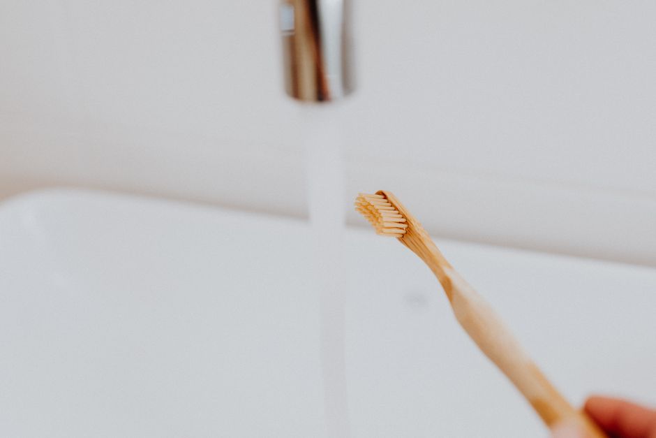 Close-up of a bamboo toothbrush with water running, emphasizing eco-friendly dental care.