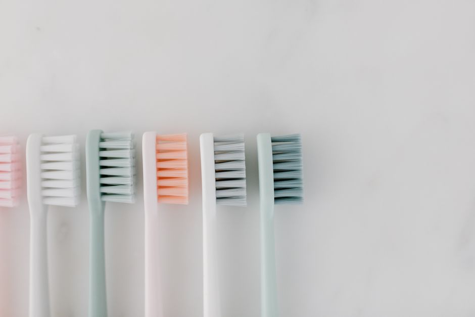 Top view of pastel-colored toothbrushes on a marble surface, ideal for dental care concepts.