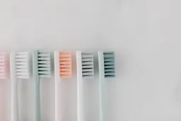 Top view of pastel-colored toothbrushes on a marble surface, ideal for dental care concepts.